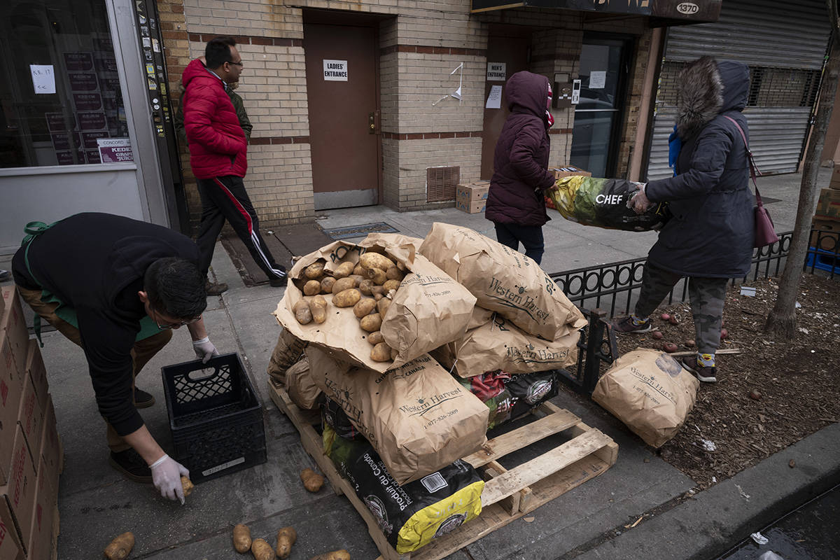 A manager at Masbia Soup Kitchen picks up spilled potatoes that are being distributed during th ...