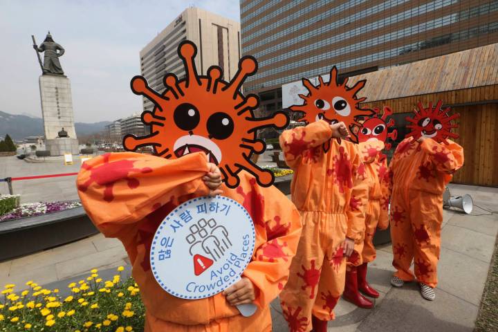 Environmental activists wearing masks symbolizing a virus perform during a new coronavirus prev ...