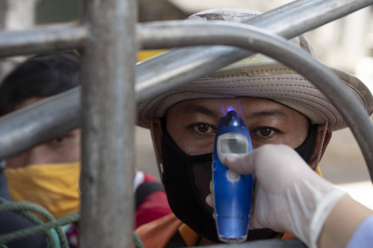 A health officer checks the temperature of a passenger in truck at a health check point in Bang ...