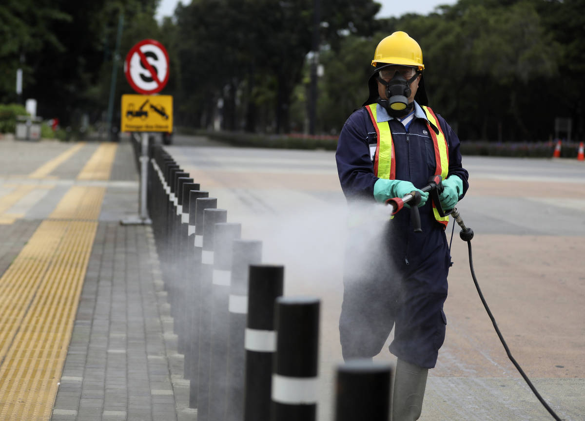 A worker sprays disinfectant at the pedestrian walkway at Senayan Sports Complex amid coronavir ...