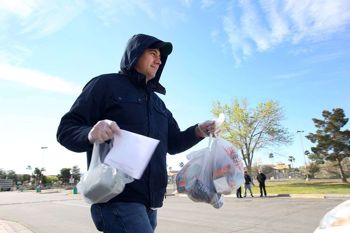 Clark County School District employee Miguel Zazueta helps pass out food and homework assignmen ...