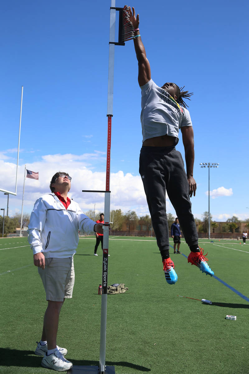 University of Hawai'i football graduate Ikem Okeke, right, leaps for the vertical jump test as ...