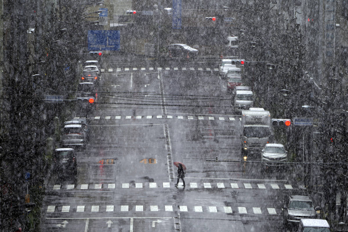 A woman walks in falling snow in Tokyo Saturday, March 28, 2020. Tokyo Gov. Yuriko Koike has re ...