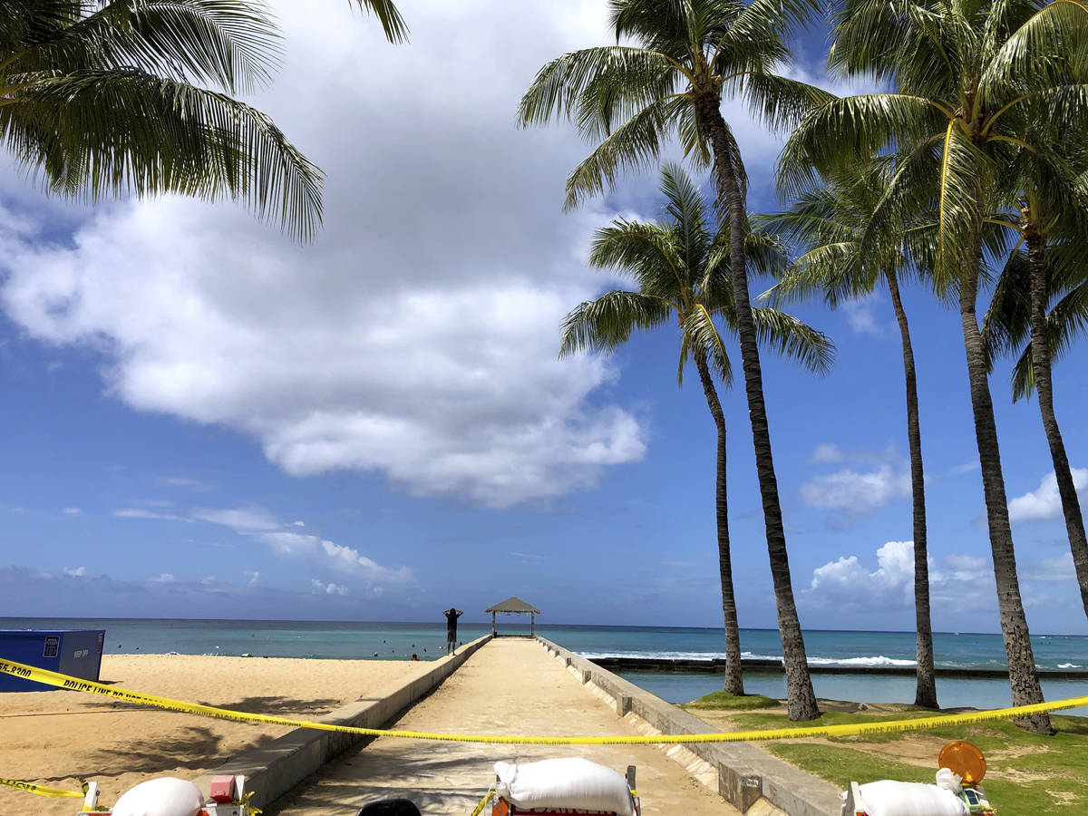 A man walks along a closed pier on Waikiki Beach in Honolulu on Saturday, March 28, 2020. (AP P ...