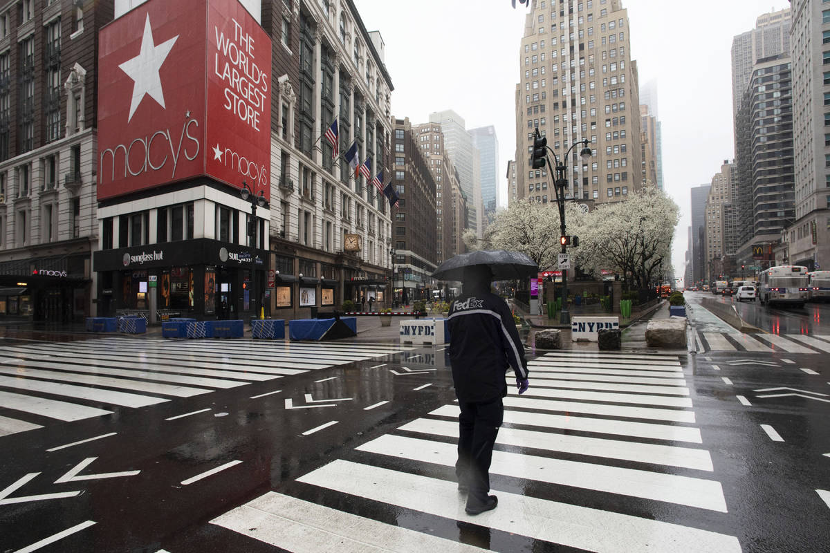 a man crosses the street in front of Macy's in New York City. Macy's is furloughing most of its ...