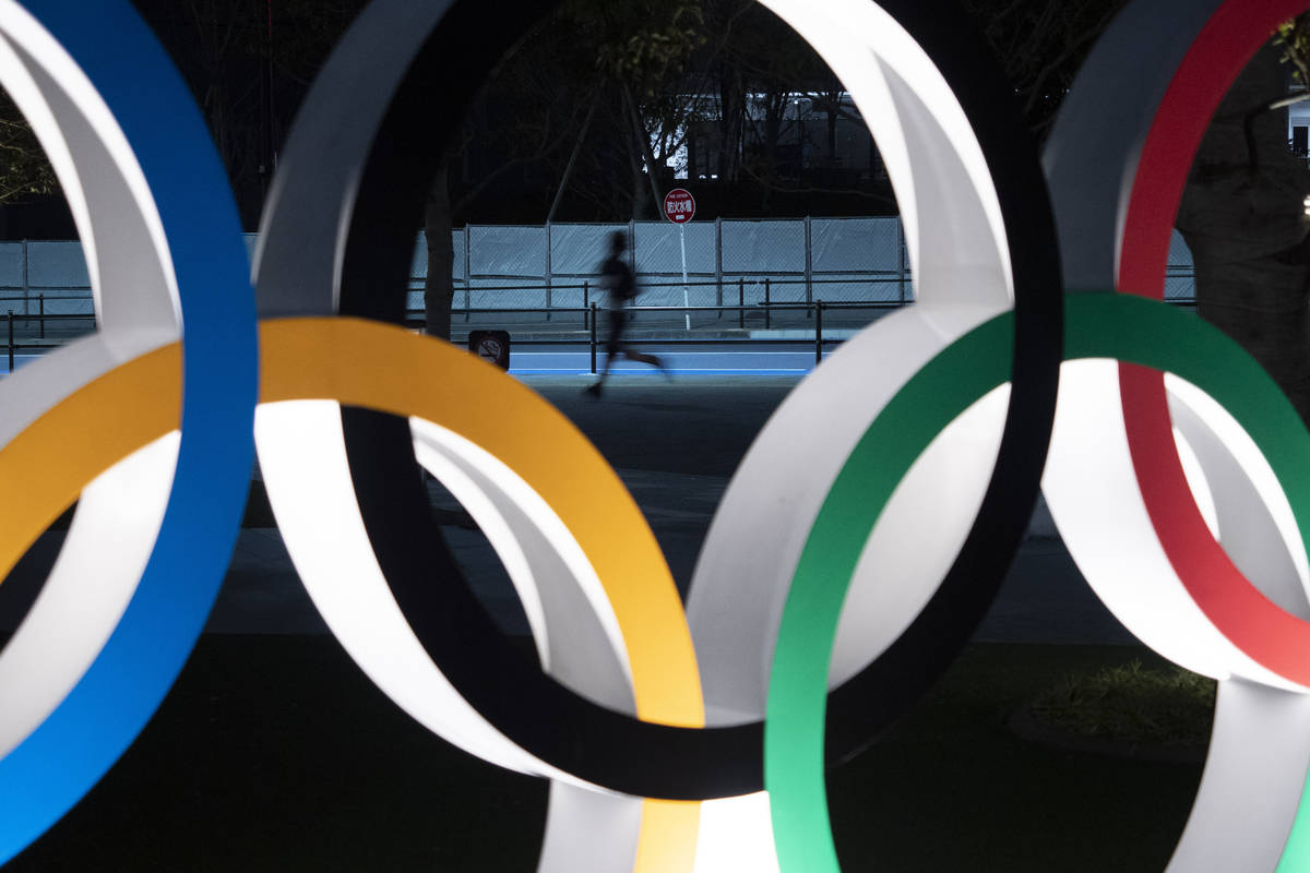A man jogs past the Olympic rings Monday, March 30, 2020, in Tokyo. The Tokyo Olympics will ope ...