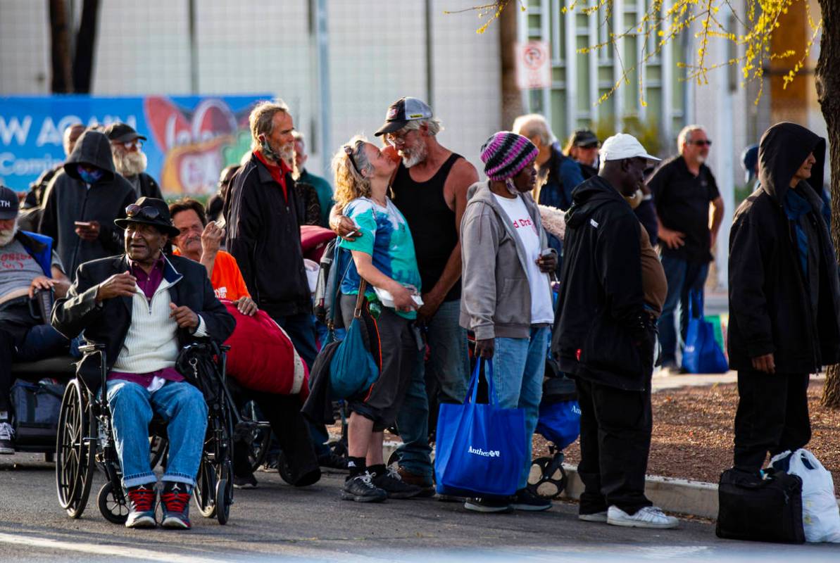 Homeless people line up to be screened to enter a temporary shelter in the upper parking lot at ...