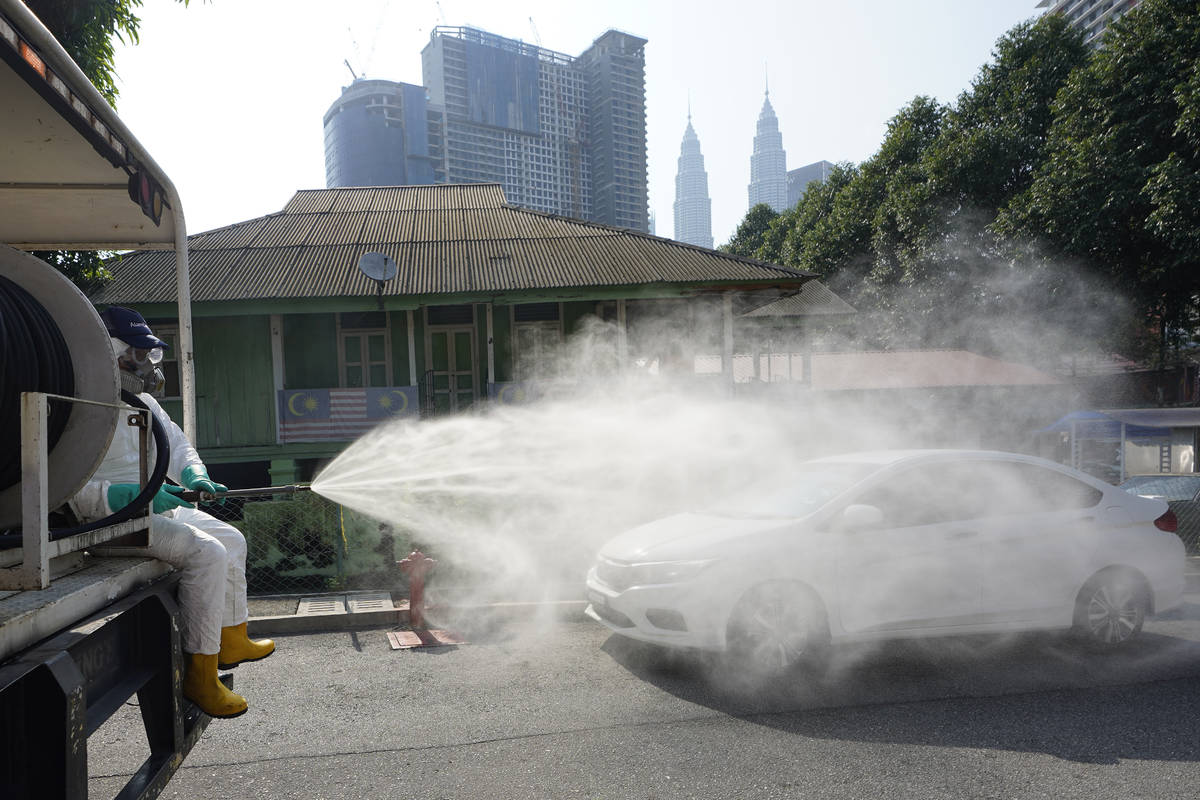 Health officials spray disinfectant in a Kampung Baru, traditional Malay village, in Kuala Lump ...
