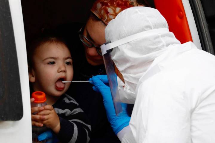 An ultra-Orthodox Jewish boy receives a COVID-19 test by a medical personnel wearing protective ...