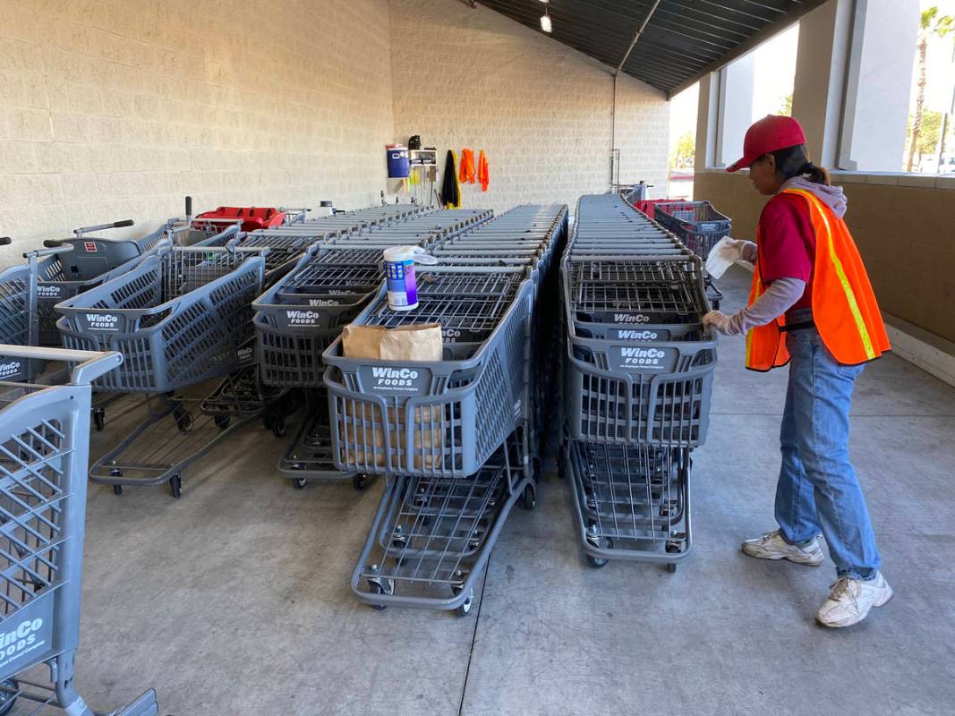 A worker sanitizes carts at WinCo Foods at 7501 Washington Ave. in Las Vegas Tuesday, March 31, ...