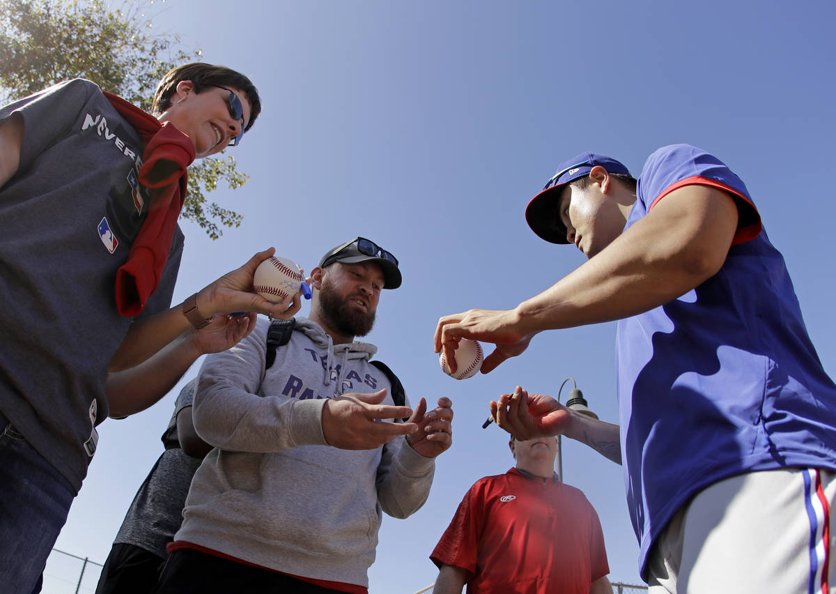Texas Rangers' Shin-Soo Choo signs autographs during spring training baseball practice Monday, ...
