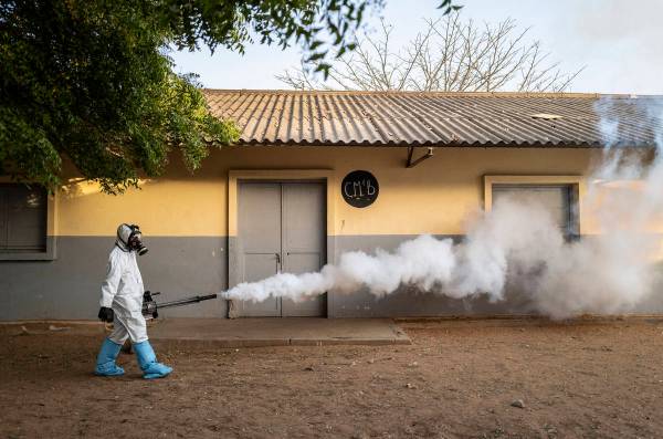 In this Wednesday, April 1, 2020, photo, a municipal worker sprays disinfectant at a school to ...