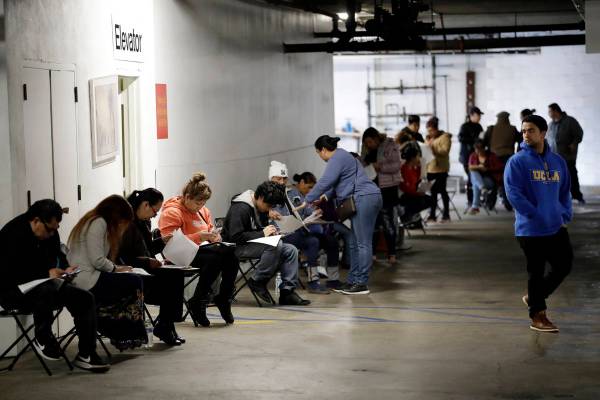 Unionized hospitality workers wait in line in a basement garage to apply for unemployment benef ...