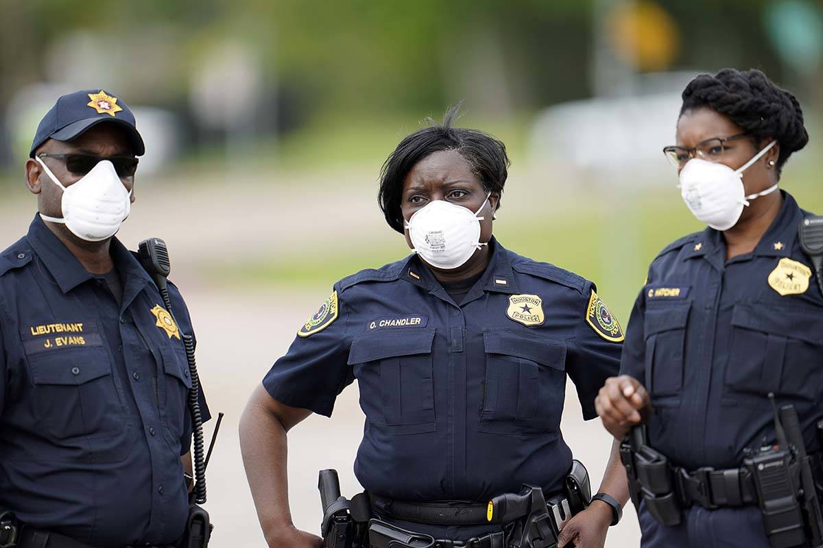 Law enforcement officers wear masks while working at a newly opened free drive through Covid-19 ...