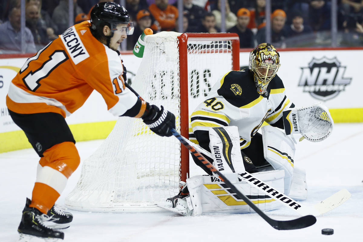 Philadelphia Flyers' Travis Konecny, left, passes the puck against Boston Bruins' Tuukka Rask d ...