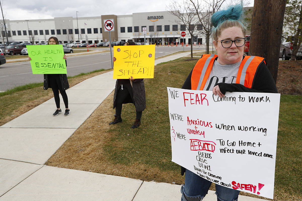Employee Tonya Ramsay, right, holds a sign outside the Amazon DTW1 fulfillment center in Romulu ...