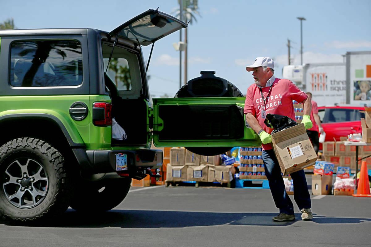 Three Square Food Bank volunteer Norman Fultz hands out food to people in their cars at Palace ...