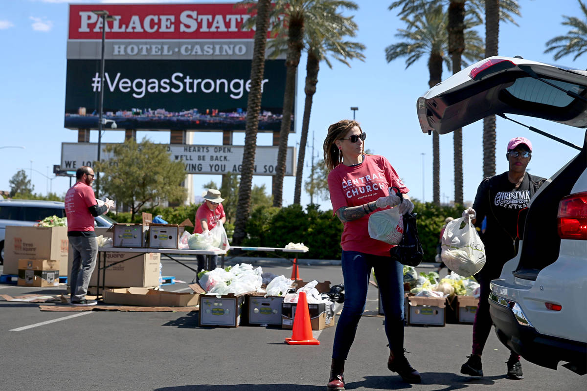 Three Square Food Bank volunteers Bobbie Bisbee, left, and Monica Smith, give out food at Palac ...