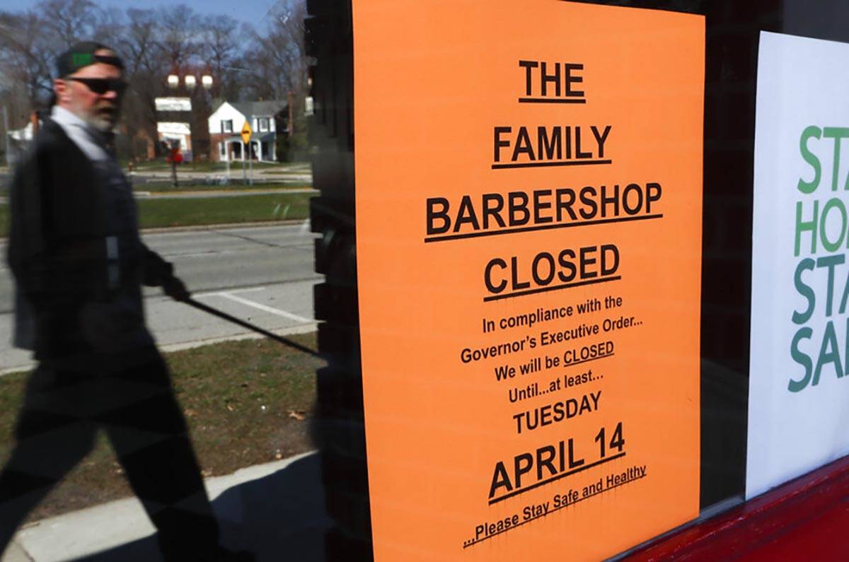 A pedestrian walks by The Family Barbershop, closed due to a Gov. Gretchen Whitmer executive or ...