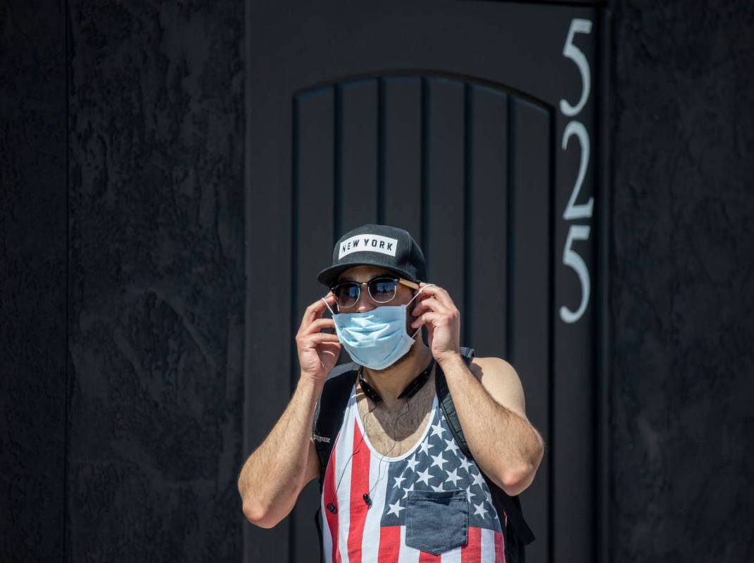 Jesse Cintron puts on a protective mask in downtown Las Vegas on Friday, April 3, 2020. (Benjam ...