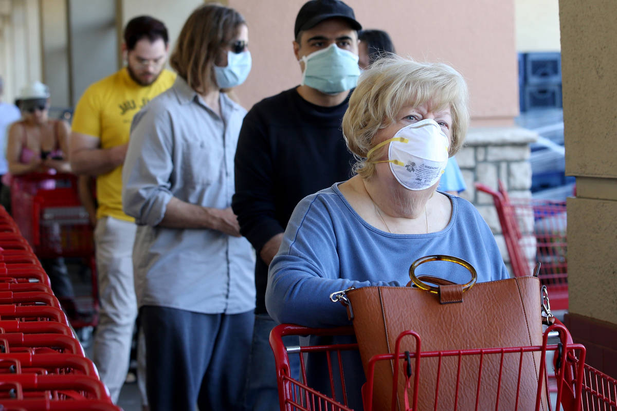 Shoppers, including Eileen Frey of Las Vegas, right, wear masks while waiting in line at Trader ...