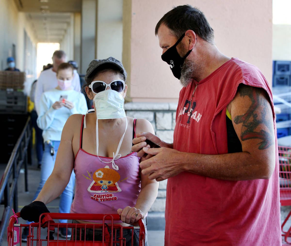 Rebellee Mohadjerani and Derek Harter of Las Vegas wear masks while waiting in line at Trader J ...