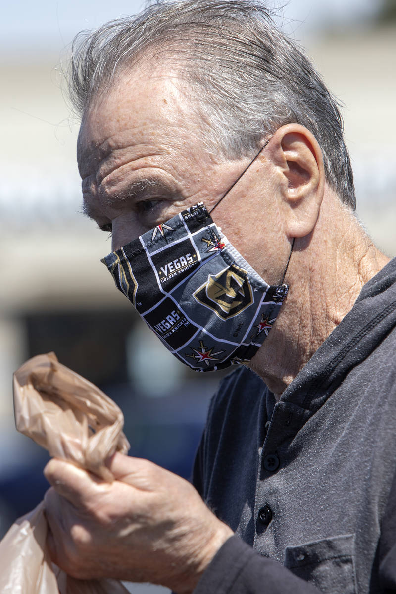 Michael McGowan wears a mask made out of Vegas Golden Knights fabric as he loads his car in the ...