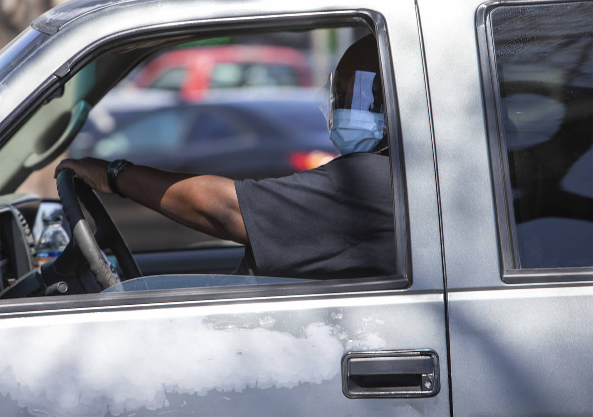 A driver wears a mask and face shield in the parking lot of the Smith's Food and Drug on South ...