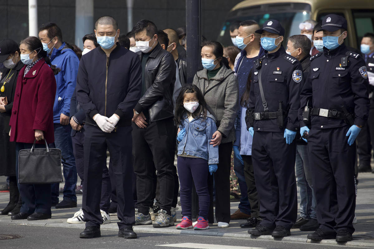 People bow their heads during a national moment of mourning for victims of coronavirus in Wuhan ...