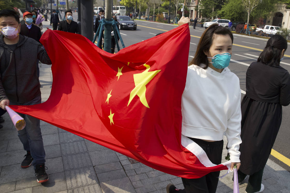 People hold a Chinese flag as they gather outside of a park where an official memorial was held ...