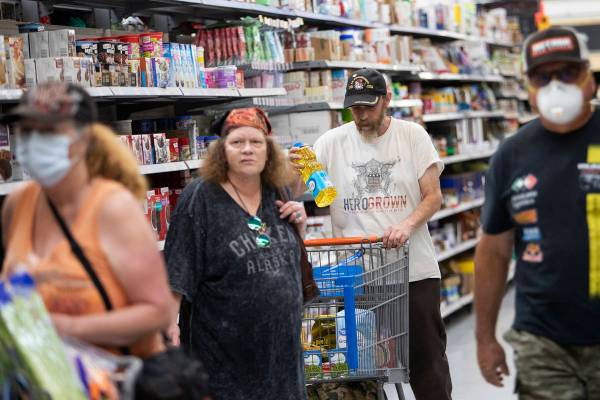 Debbie Holmgren and Todd Henke, flanked by two masked shoppers, pick up groceries at Walmart on ...