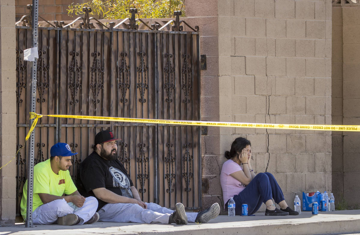 Individuals sit inside of crime tape as the Las Vegas police investigate a reported homicide on ...