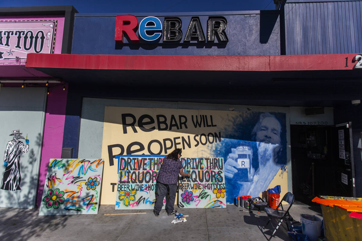 Geneva Marquez paints signage at ReBAR in the Arts District on Saturday, April 4, 2020, in Las ...