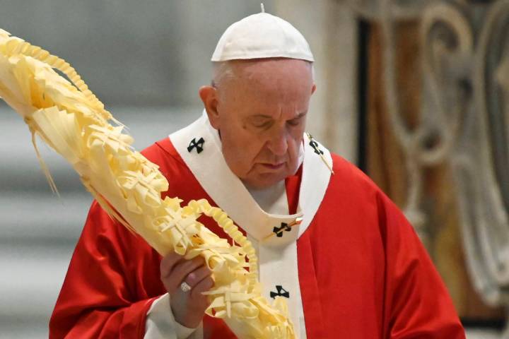 Pope Francis holds a palm branch as he celebrates Palm Sunday Mass behind closed doors in St. P ...