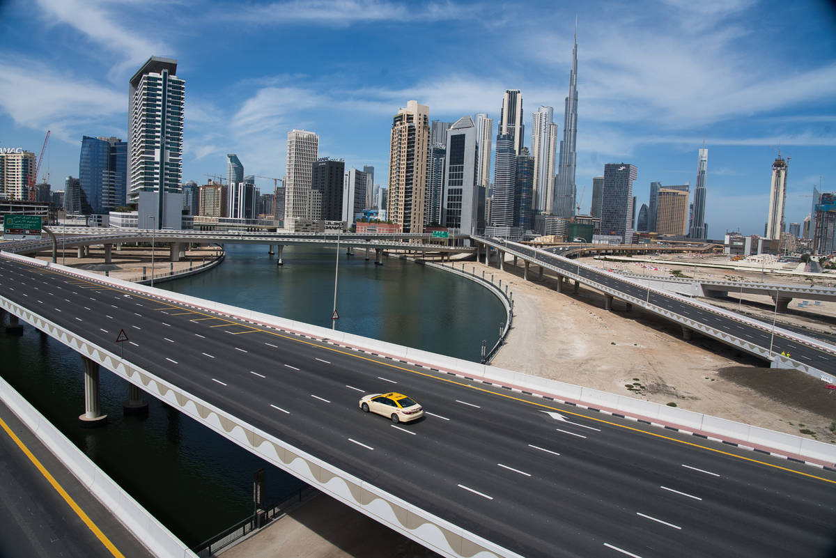 A lone taxi cab drives over a typically gridlocked highway with the Burj Khalifa, the world's t ...