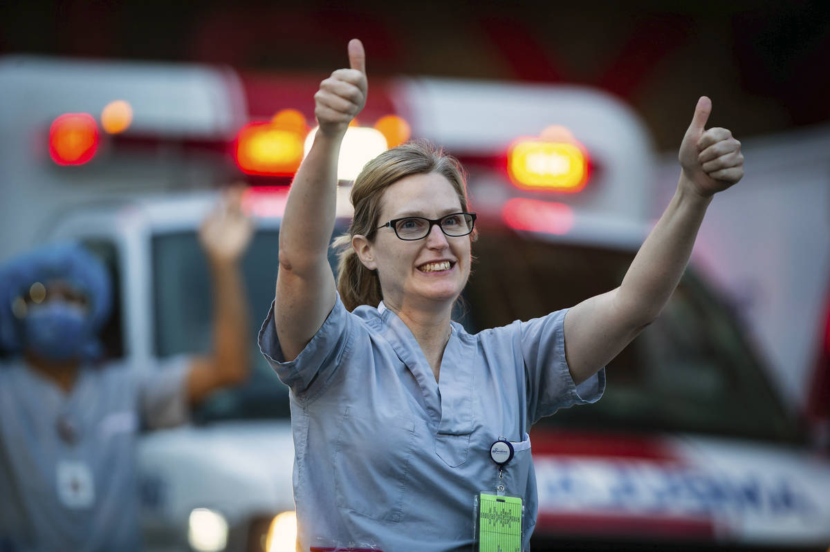 A healthcare worker at St. Paul's Hospital acknowledges applause and cheers from people outside ...