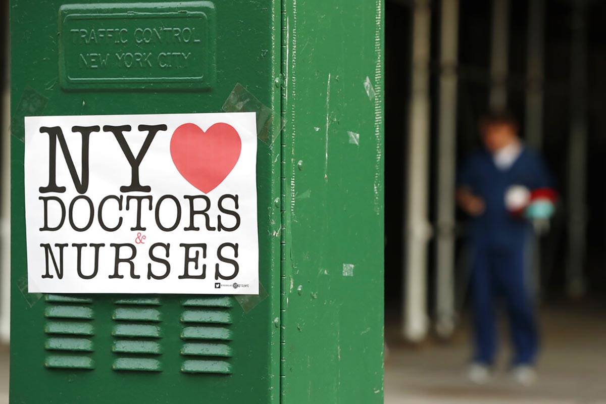 A sign acknowledging the work of doctors and nurses is posted on a traffic control box outside ...