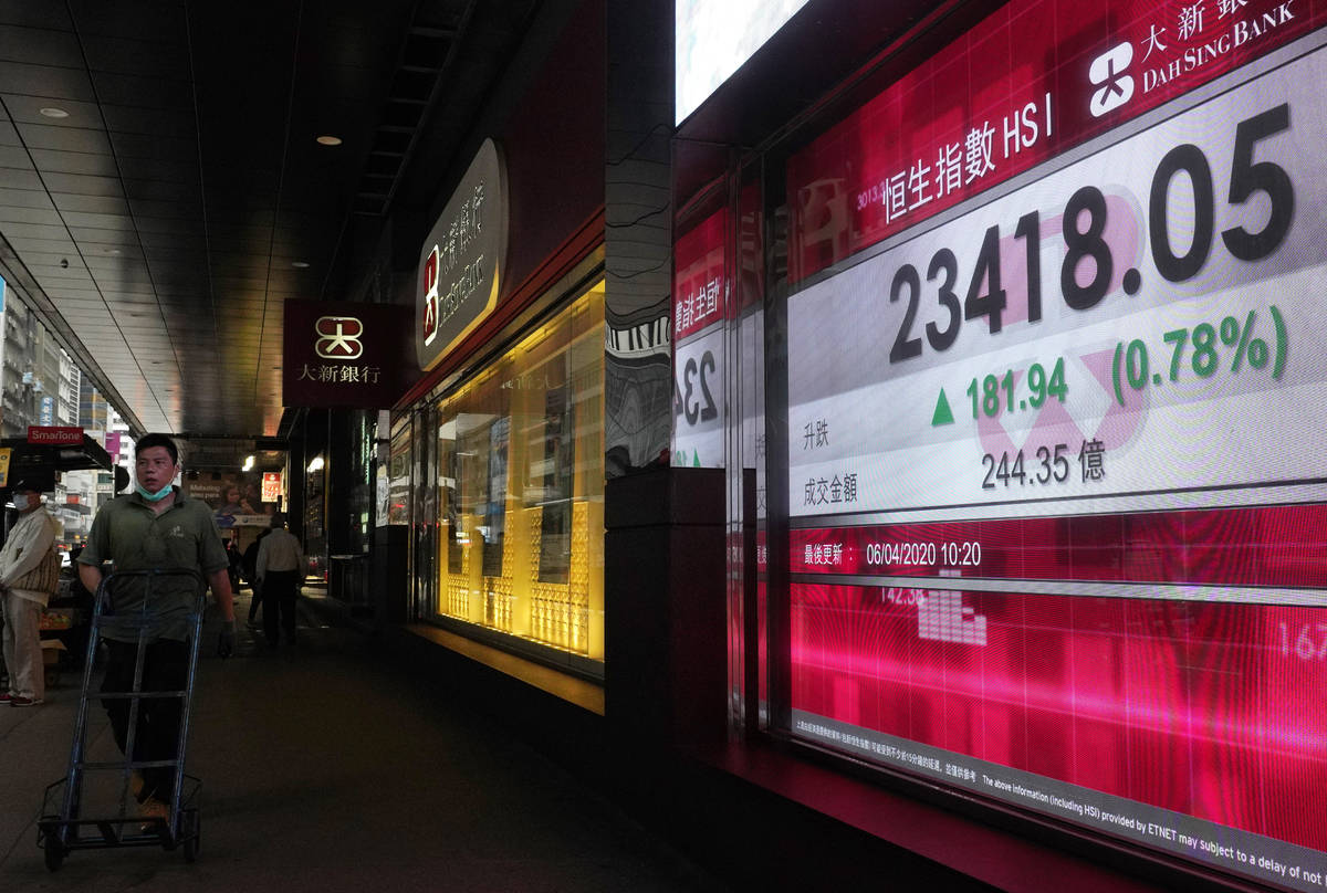 A man wearing face mask walks past a bank electronic board showing the Hong Kong share index at ...