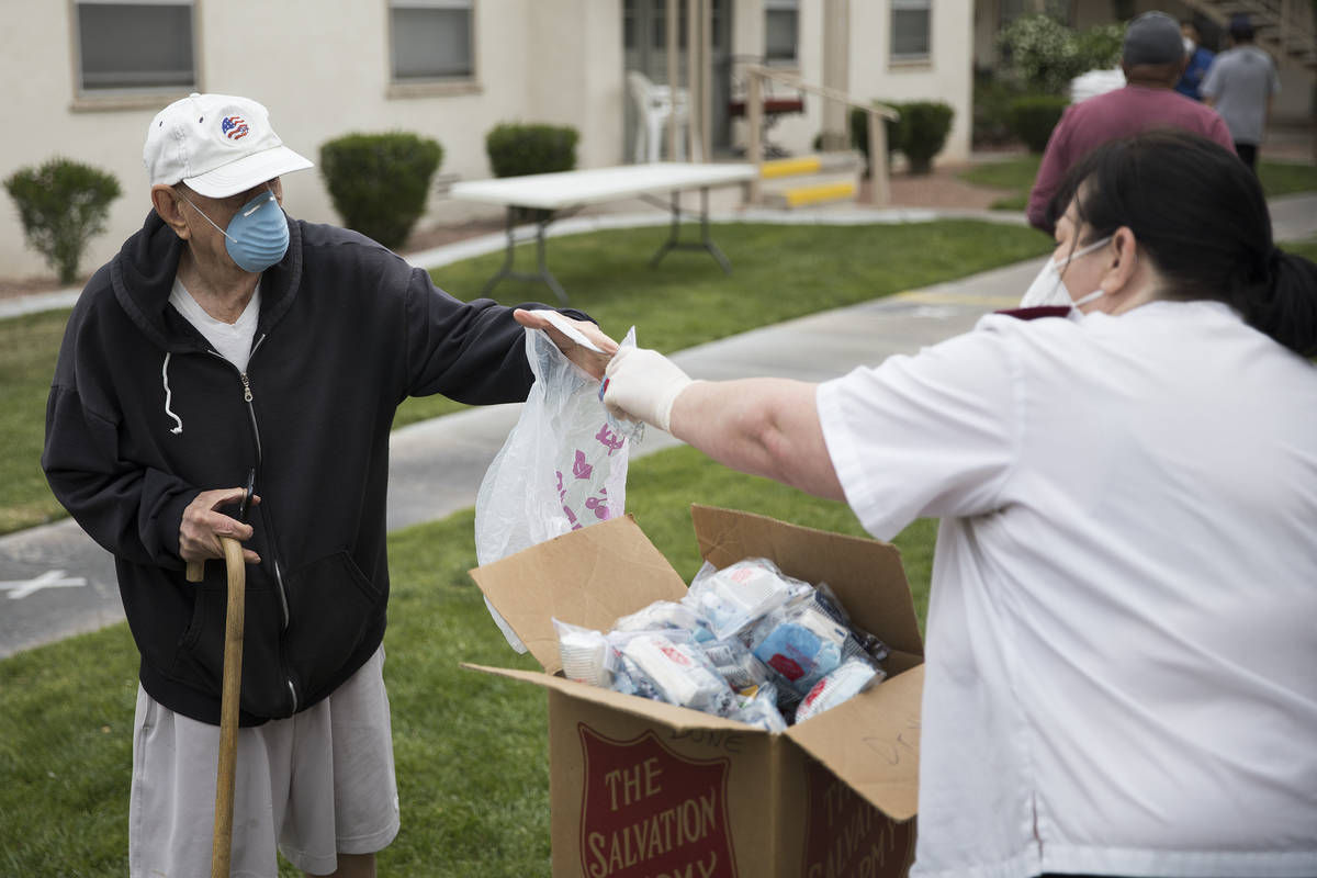 Heather Baze, a lieutenant with the Salvation Army, hands out a coronavirus preparedness kit to ...