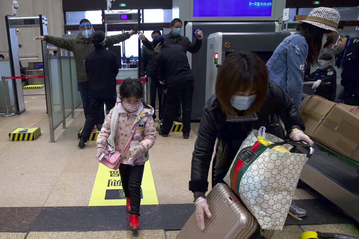 Passengers wearing face masks to protect against the spread of new coronavirus pass through sec ...