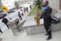 Olu Sijuwade, of Milwaukee, plays a tenor saxophone for those waiting in line to vote at Rivers ...