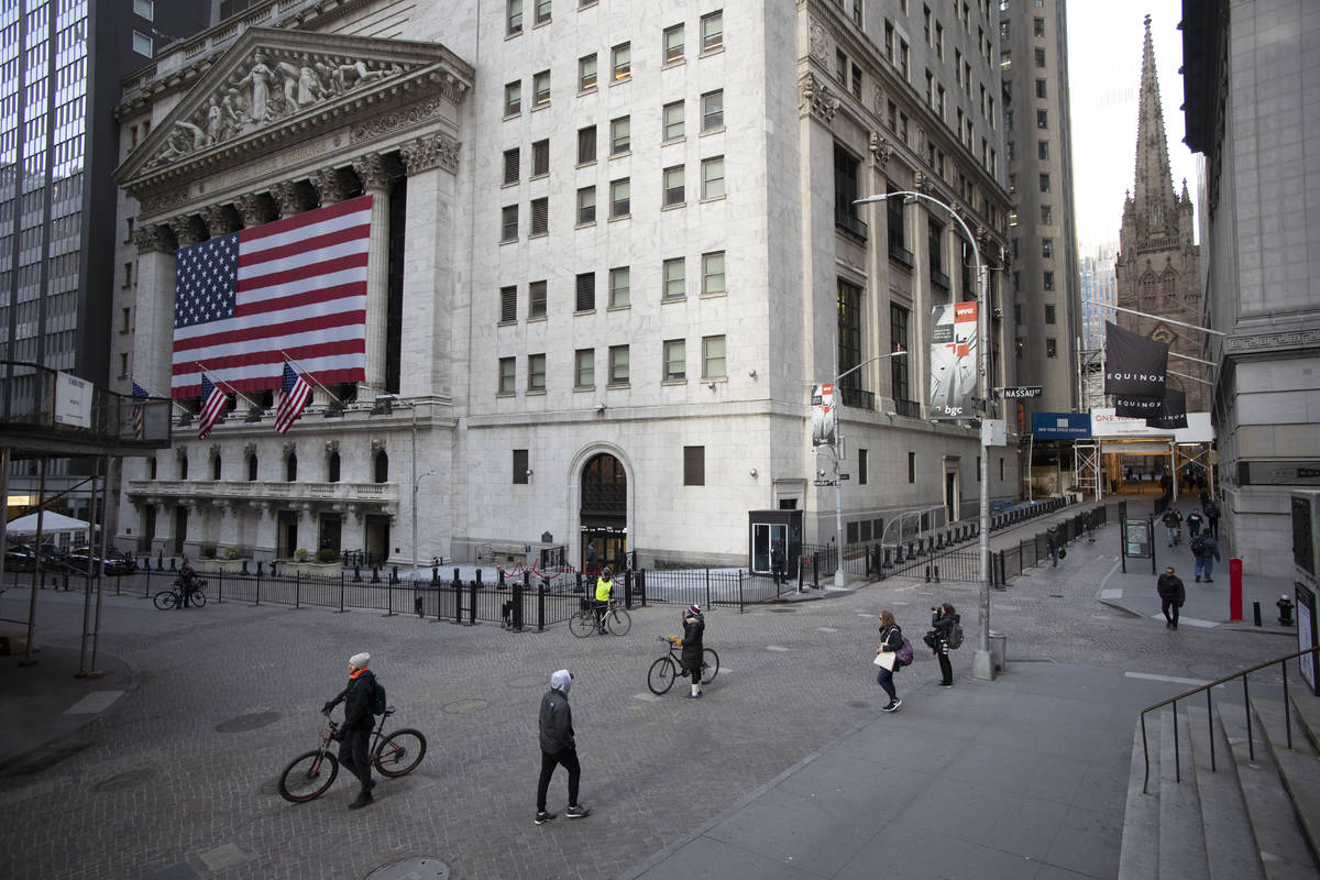 FILE- In this March 18, 2020, file photo a few people walk on Wall Street in front of the New Y ...