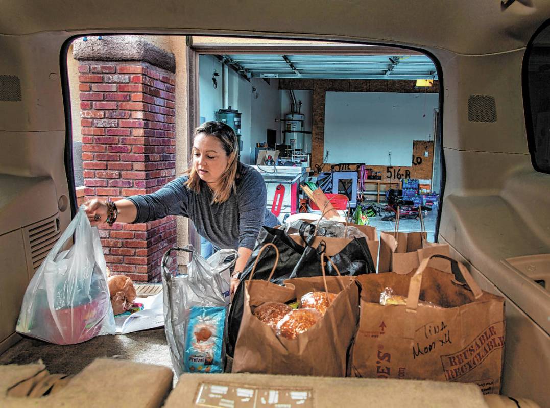 Kat Morris fills the back of her car with food and supplies for another donation drop with the ...