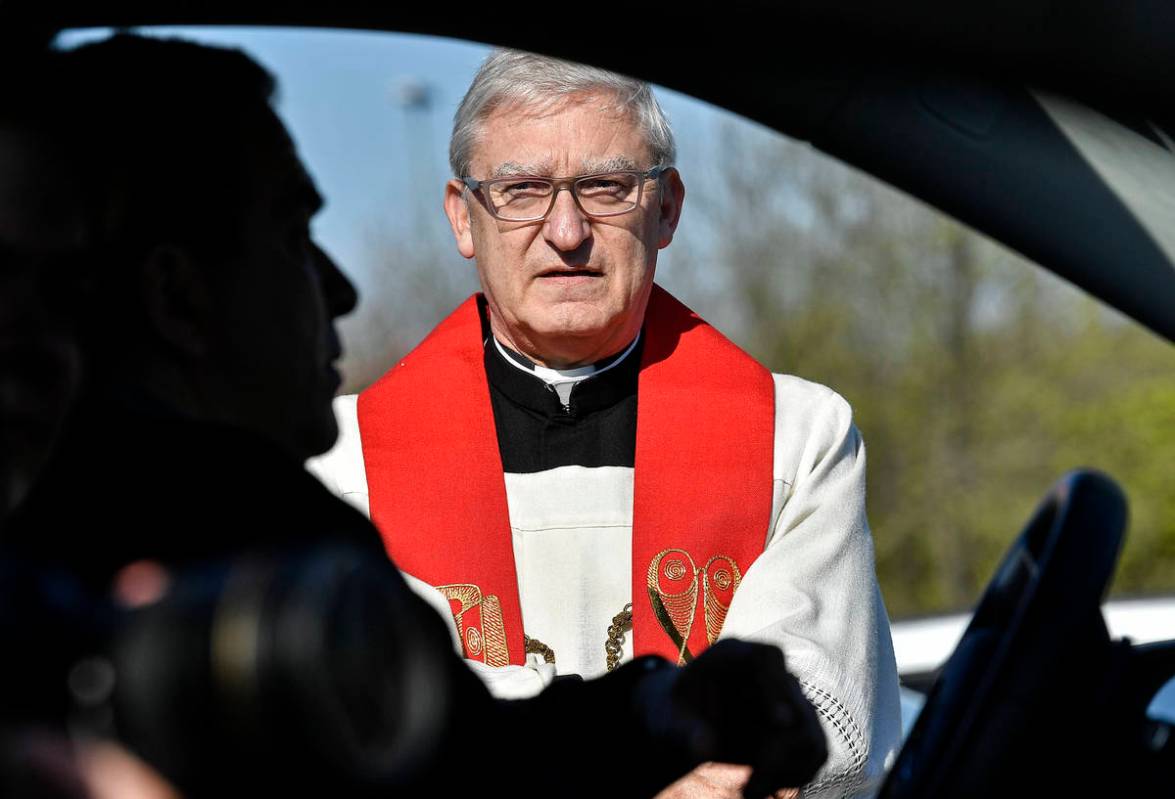 Priest Frank Heidkamp talks to believers in their cars prior a Good Friday church service at a ...