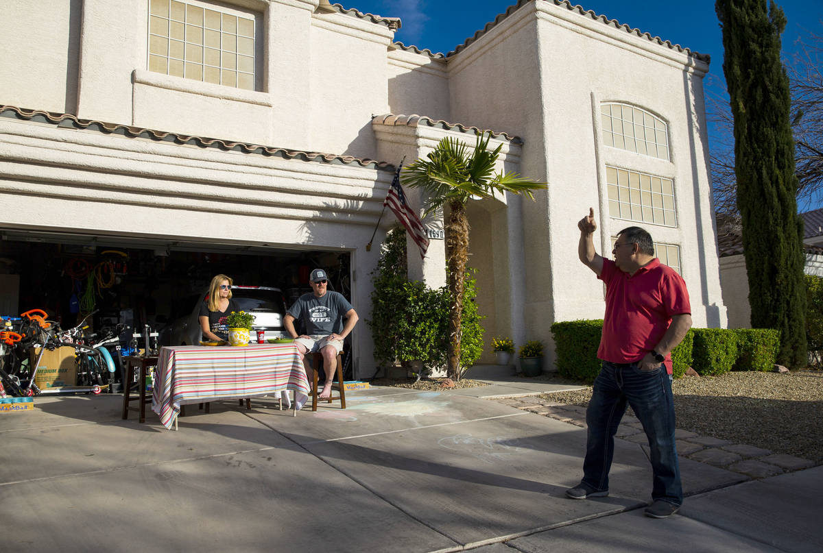 Juan Zamora, right, talks with neighbors Marie Bickel and Jeff Bickel from a distance during a ...