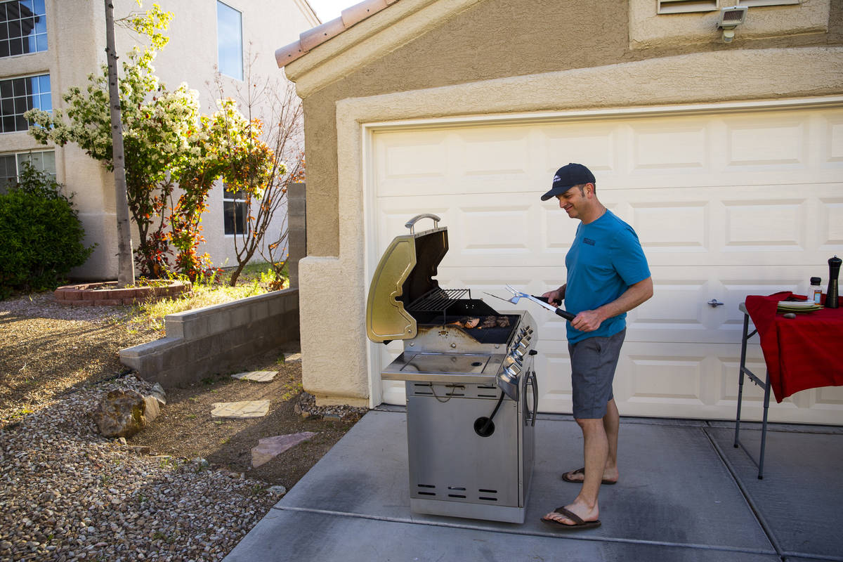 Kenny Atcheson grills outside of his home while participating in a neighborhood front yard part ...