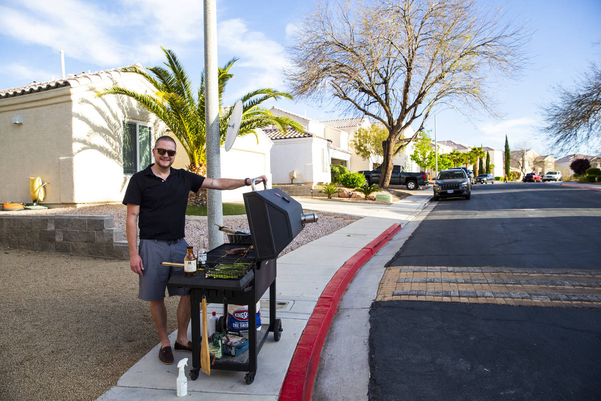 Noah Cross grills outside of his home while participating in a neighborhood front yard party an ...