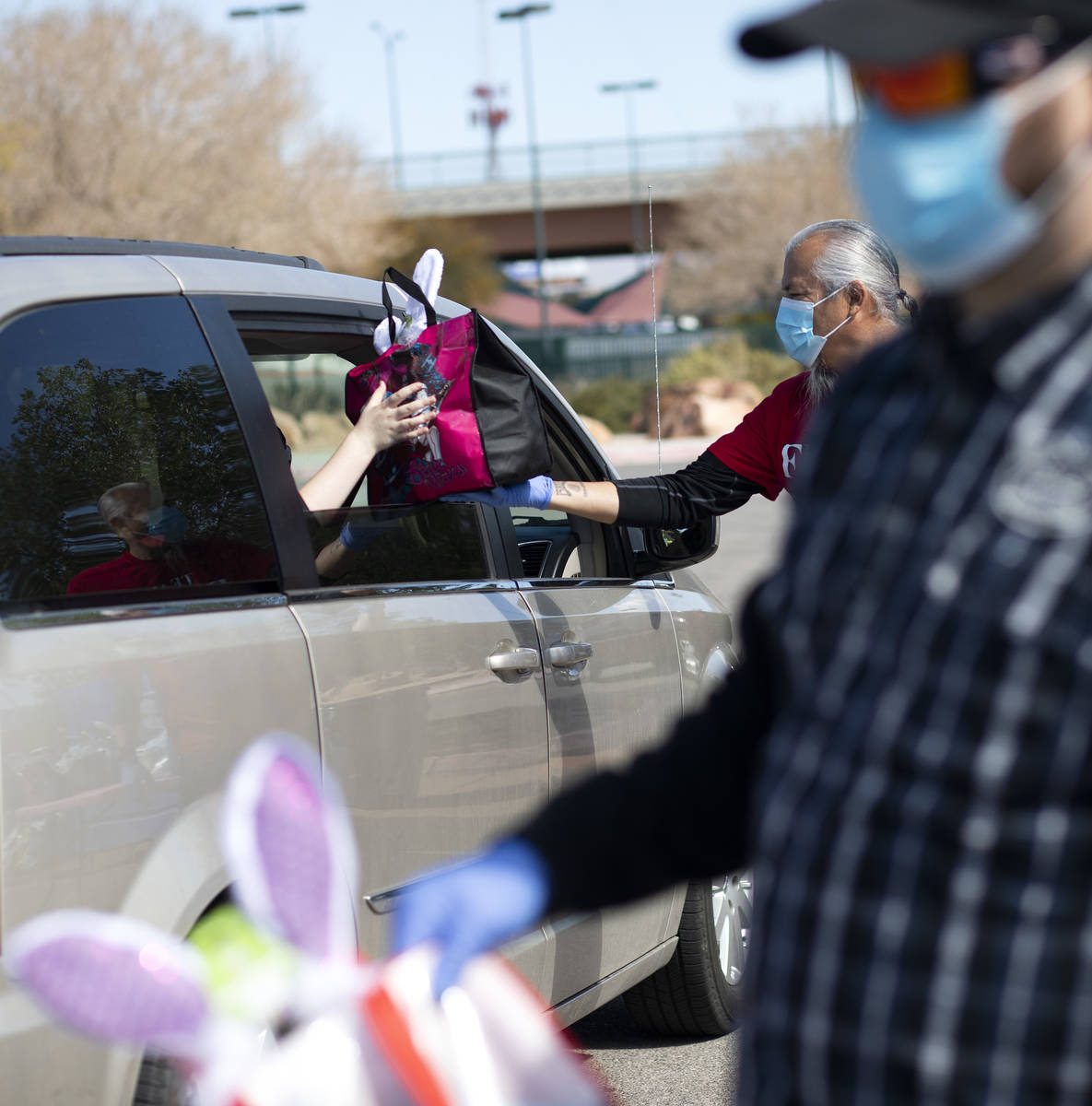 Volunteers hand out Easter baskets in a drive through procession at Mountain Ridge Park on Satu ...