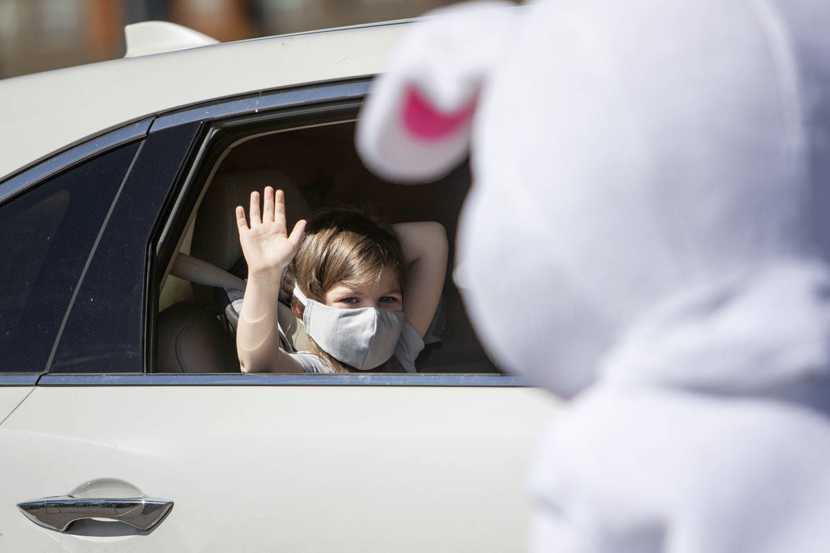 A girl waves to the Easter Bunny as she drives through to pick up her Easter basket at Mountain ...