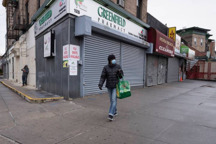 In this Friday, April 3, 2020, photo, a woman walks by local stores during the coronavirus pand ...